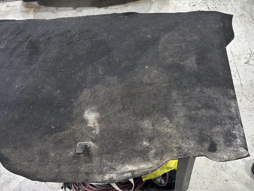 Alfombra de baúl sucia, con manchas y tierra incrustada, antes del trabajo