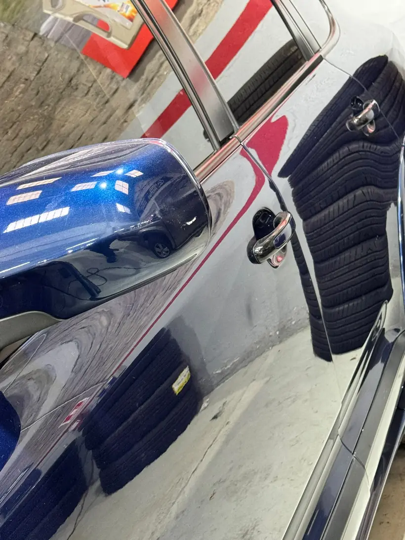 Reflejo nítido del taller sobre el lateral azul de un Porsche