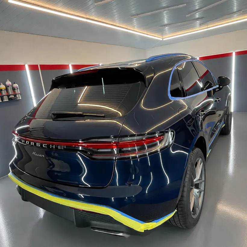 Cola de un Porsche Macan azul con cinta amarilla en el borde