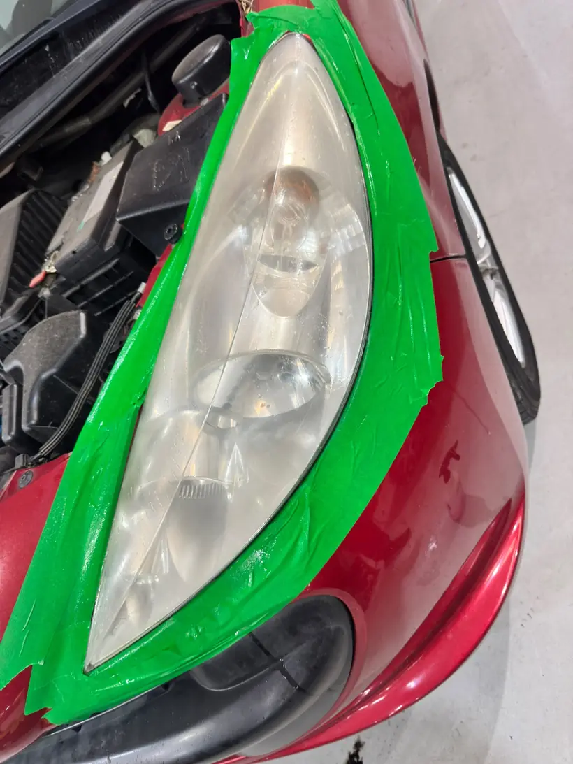 Faro delantero de Peugeot enmascarado durante el pulido