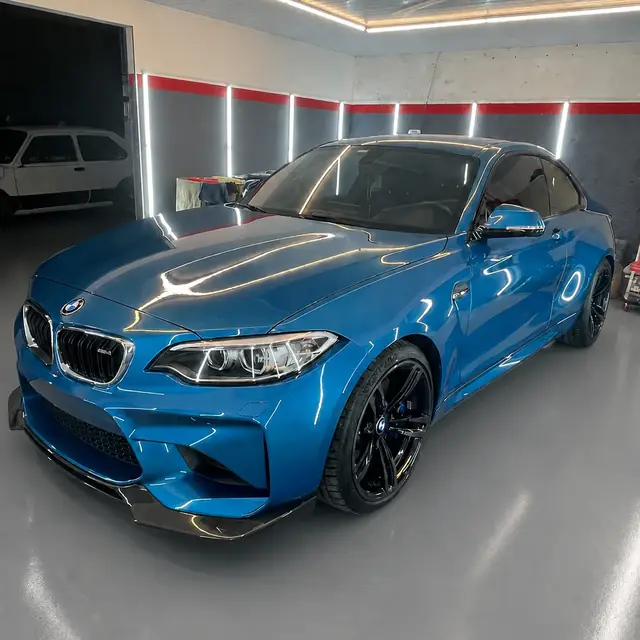 BMW M2 azul de frente, con reflejo limpio sobre el capó