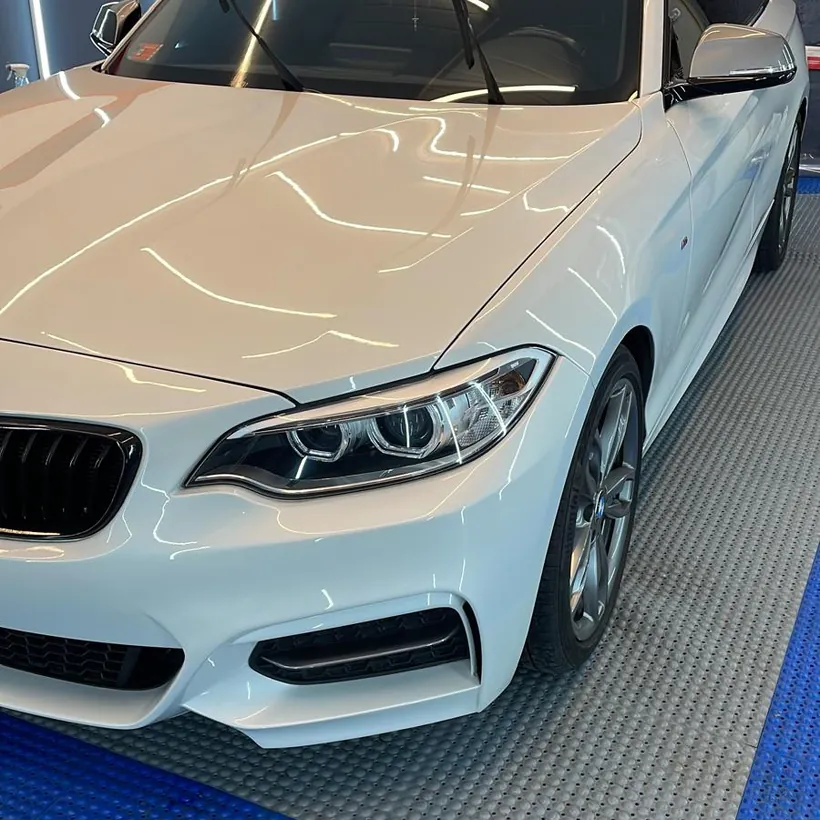 BMW blanco de frente con la optica y el capo sellados