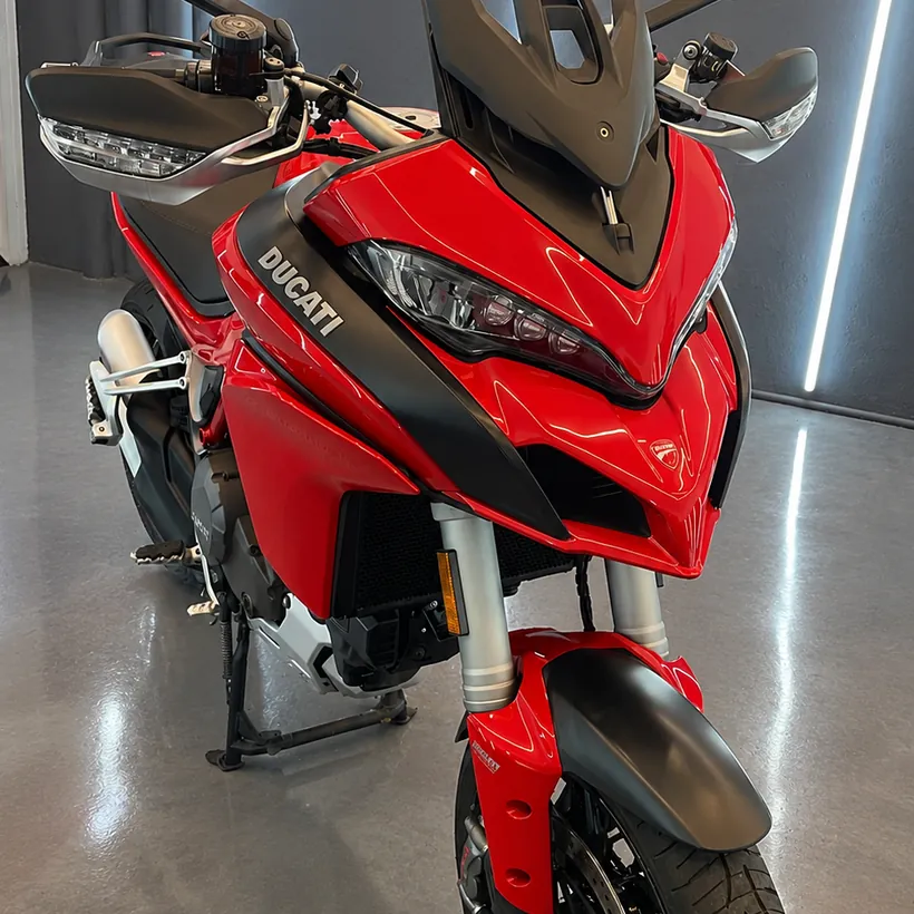 Moto Ducati roja tratada, vista de costado