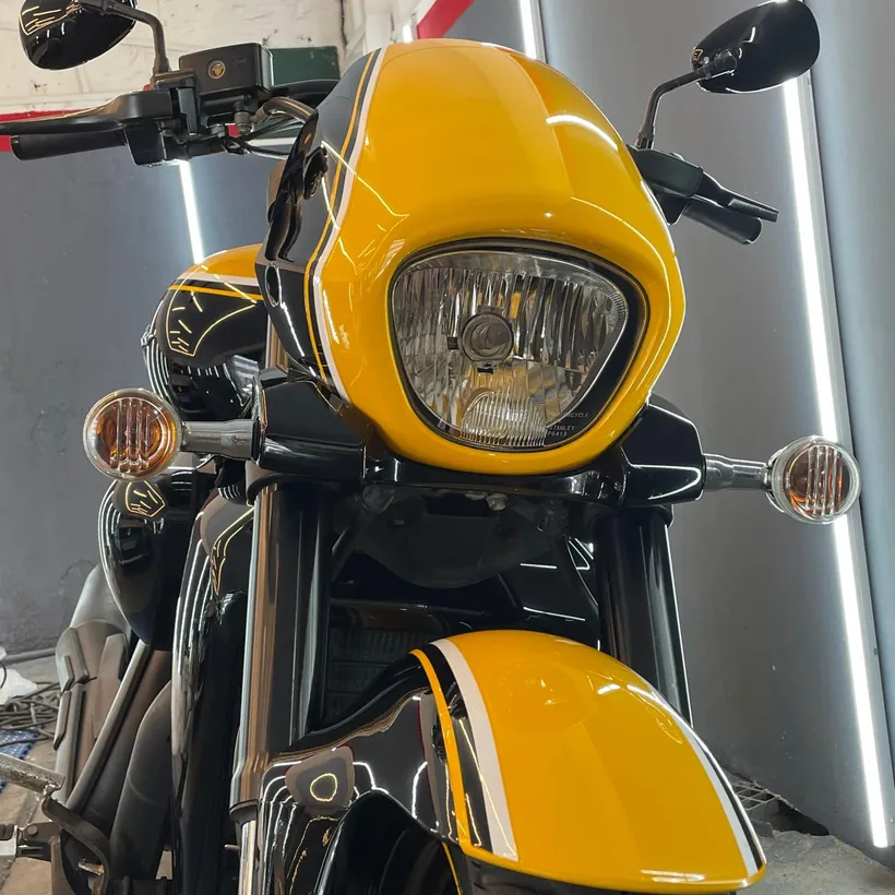 Frente de una moto amarilla con el faro pulido