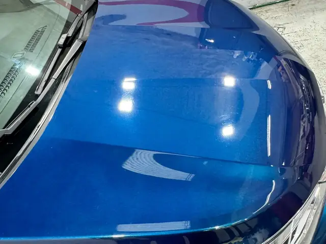 Reflejo limpio sobre capó azul con tratamiento cerámico aplicado